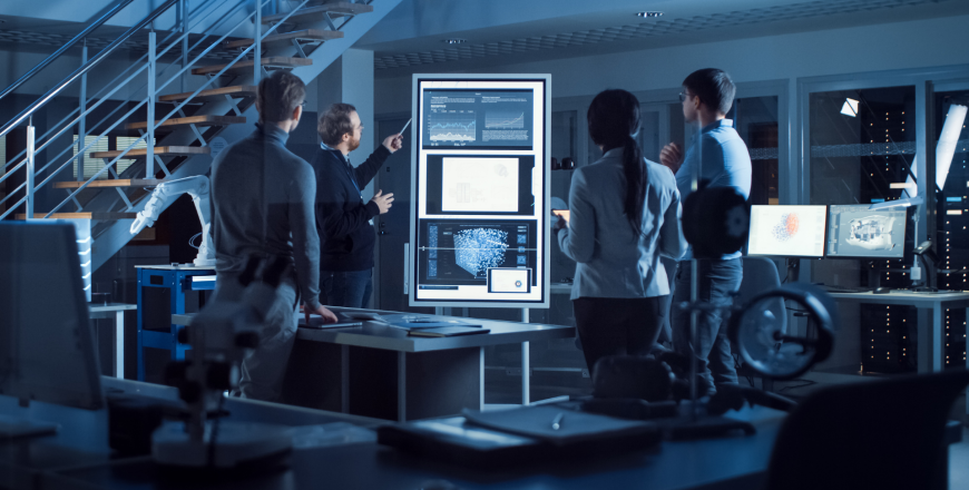 Project manager leads meeting with a team of electronic development engineers using a digital whiteboard explaining neural network technology, AI and machine learning