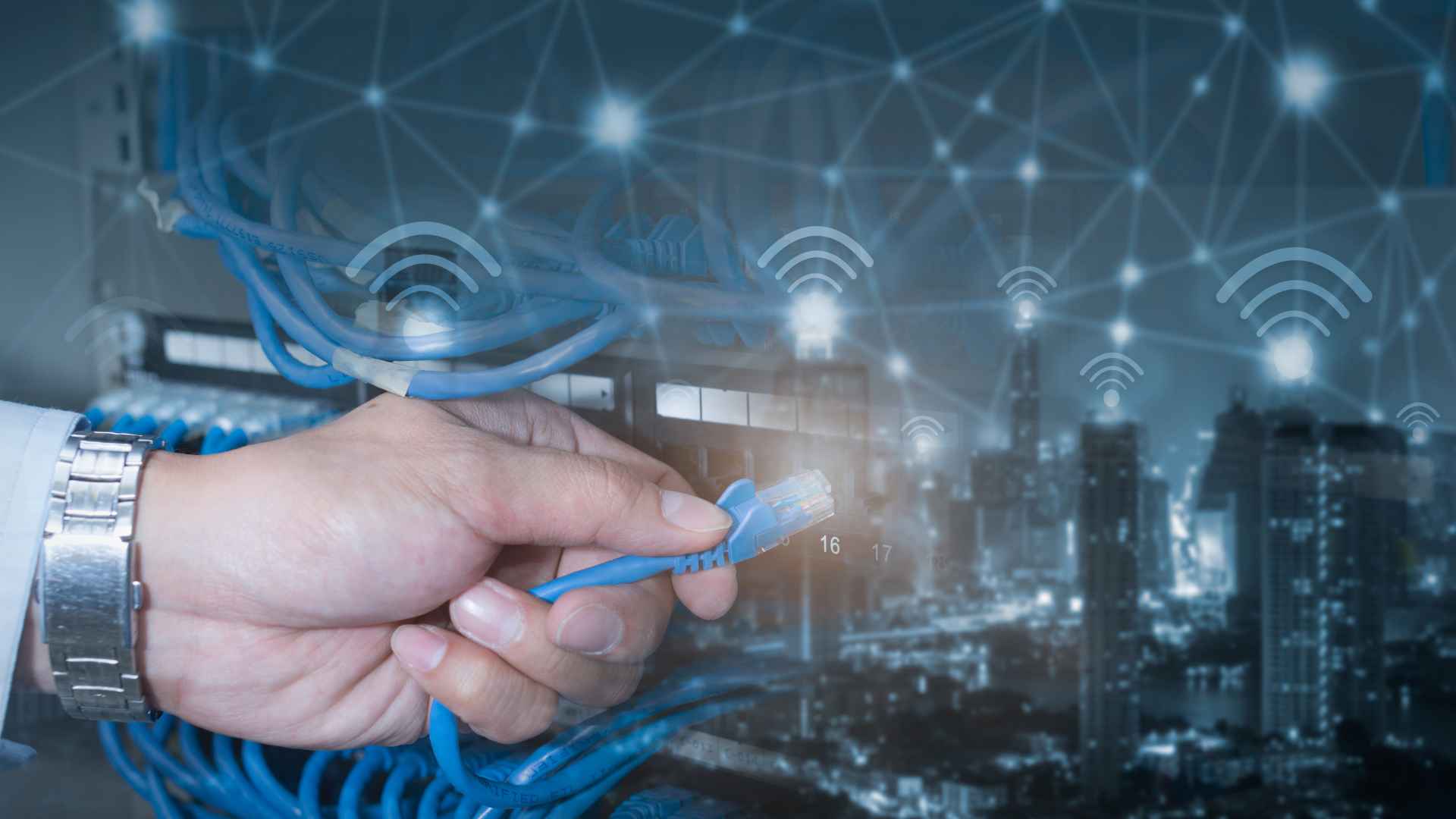 Ethernet cable held in hand by man wearing a watch against background of office buildings with WiFi connectivity