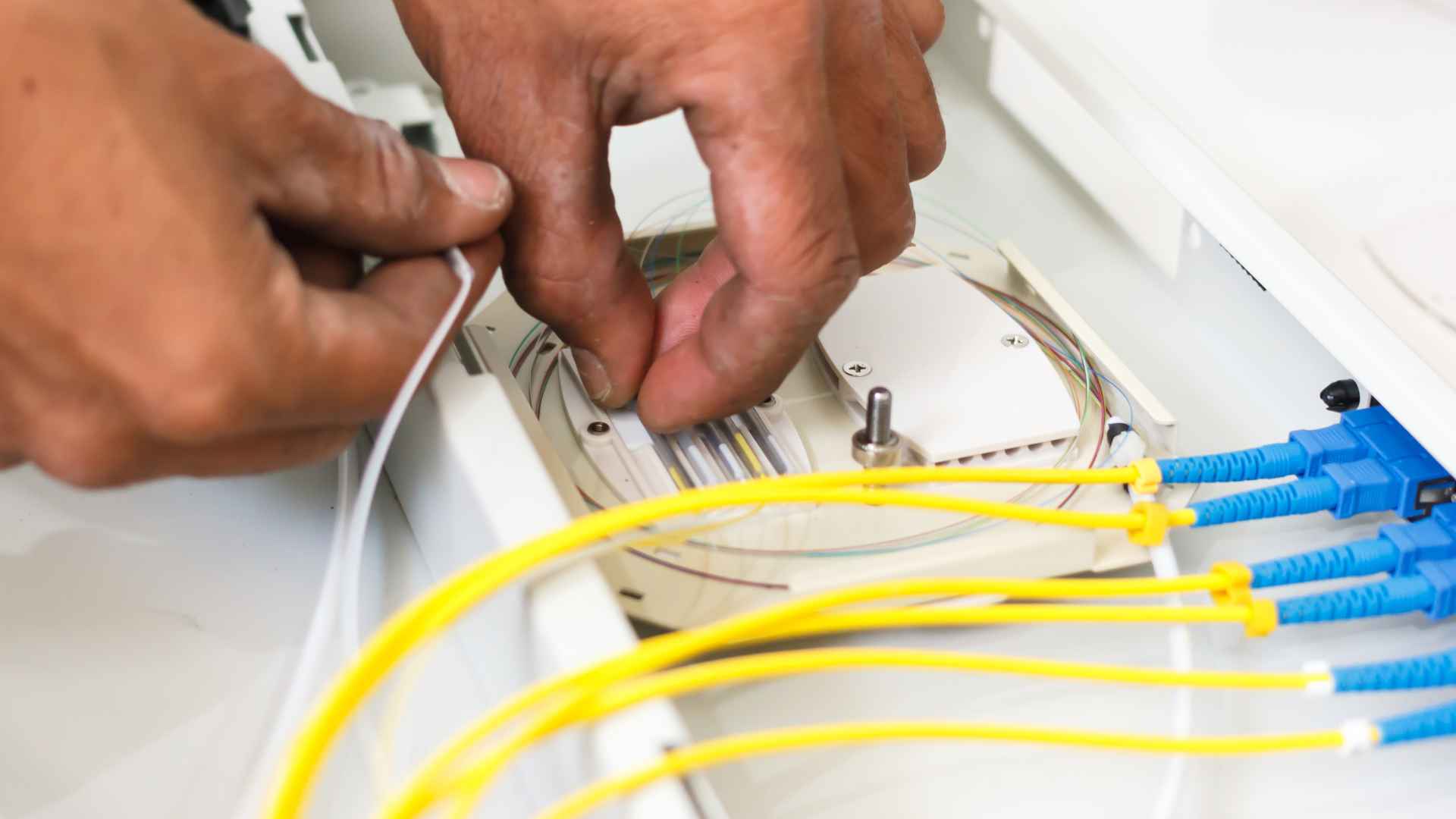 A pair of hands installing fiber optic cables
