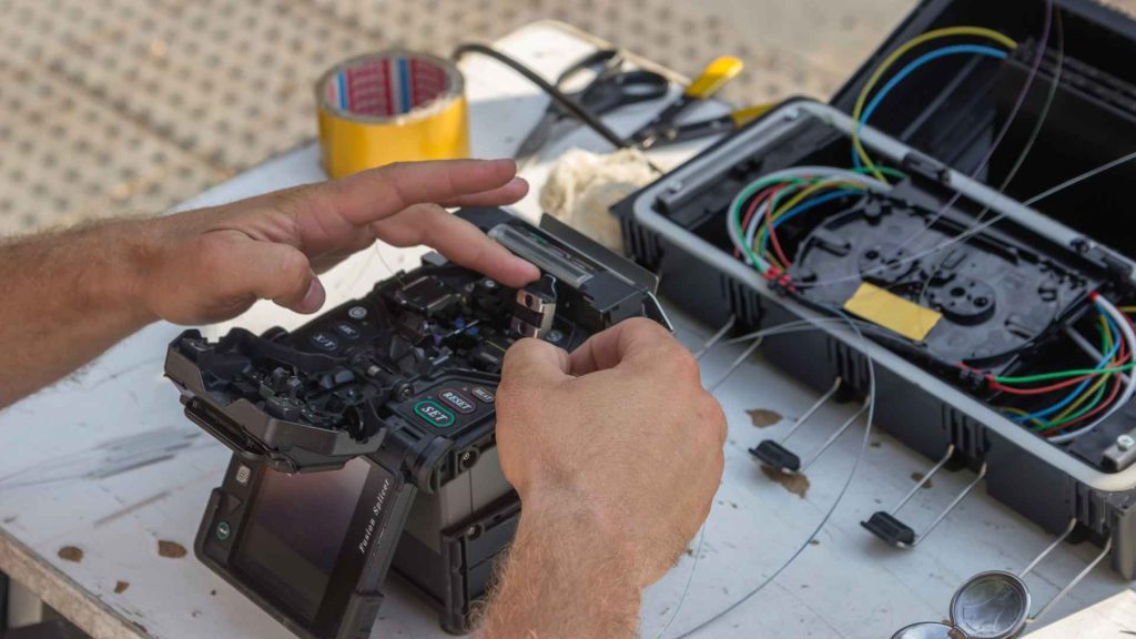 Fibre optic technician using a fusion splicer to connect fibre optic cables