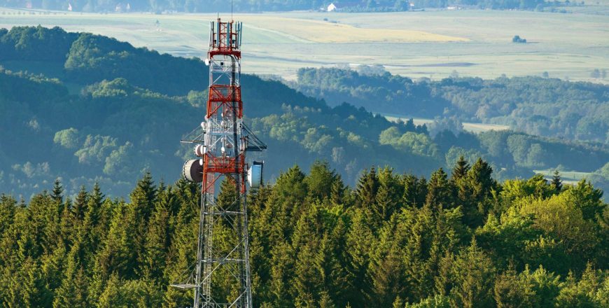 A microwave tower at the top of a hill on an aerial shot