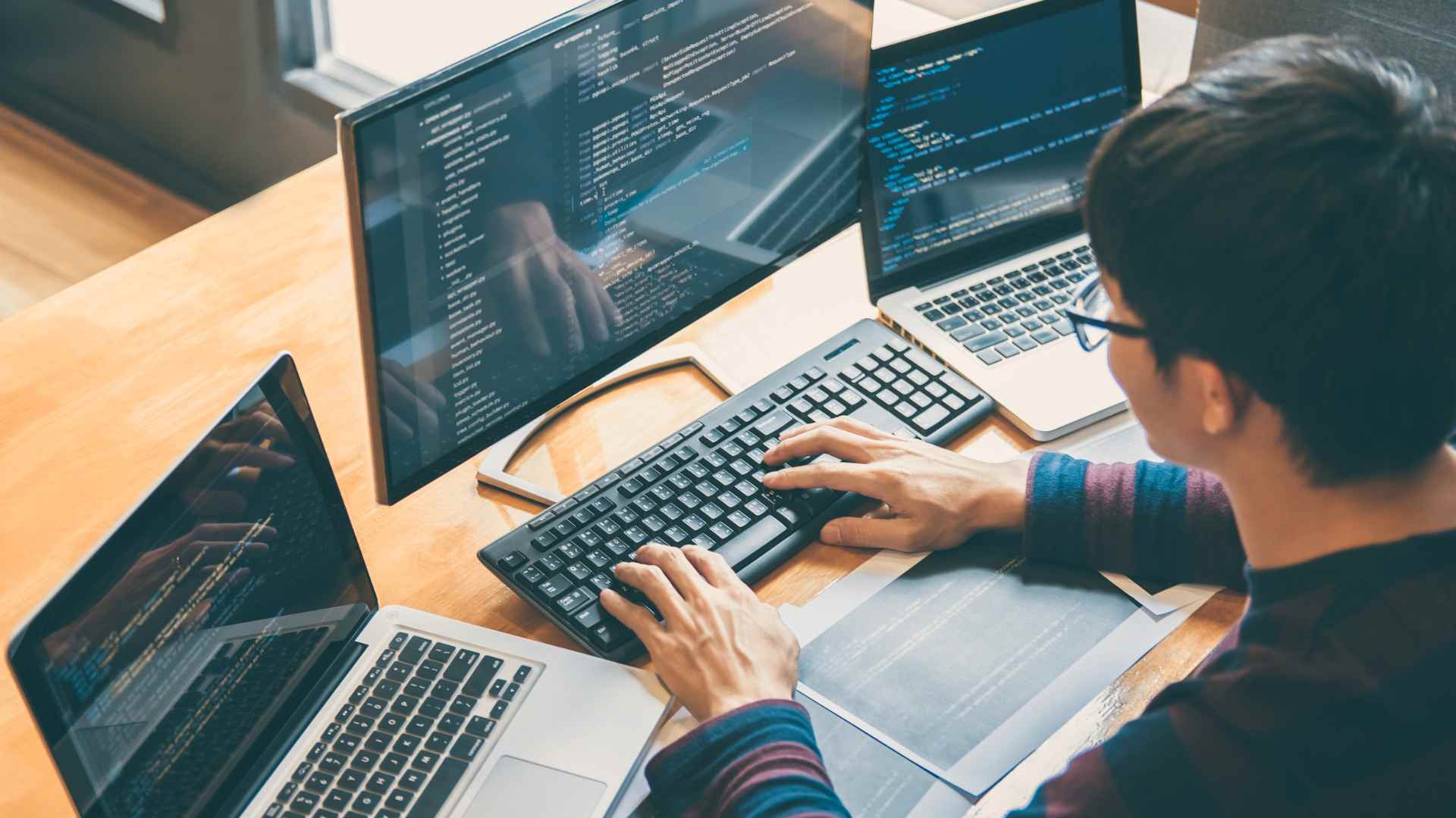 Programmer using Wireshark packet analyzer on desktop monitor for network analysis and troubleshooting