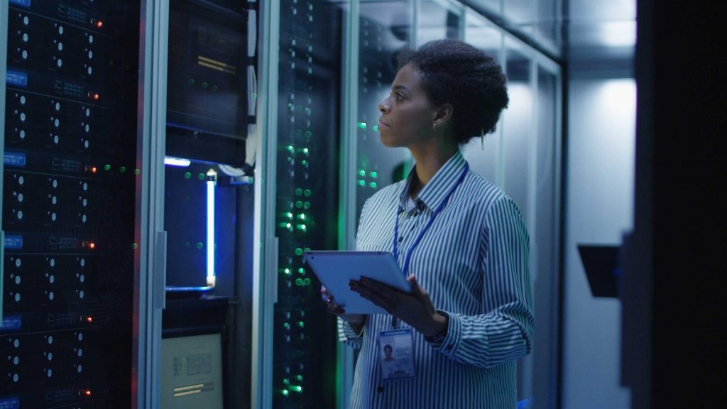 Portrait of woman working as an IT engineer and standing among server racks in data center room