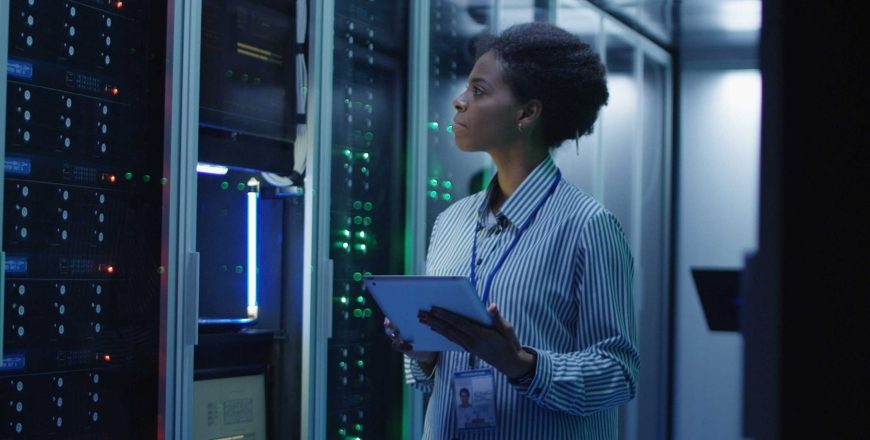 Portrait of woman working as an IT engineer and standing among server racks in data center room
