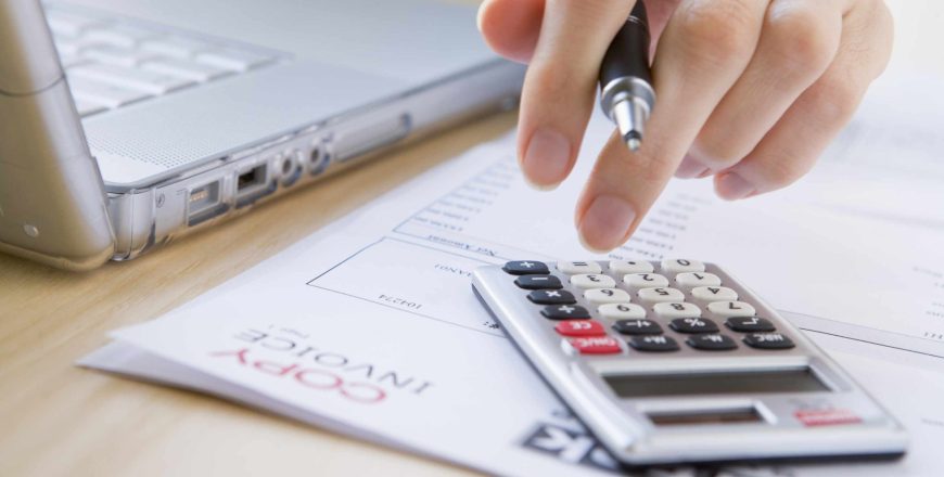 An accountant's hand pressing the keys on a calculator to calculate billing amount