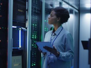 Portrait of woman working as an IT engineer and standing among server racks in data center room