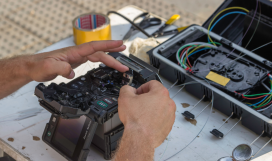 Fibre optic technician using a fusion splicer to connect fibre optic cables