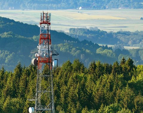 A microwave tower at the top of a hill on an aerial shot