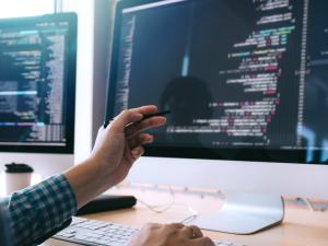 Software radio engineer points to computer screen using pen and analyzes the code