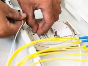 A pair of hands installing fiber optic cables