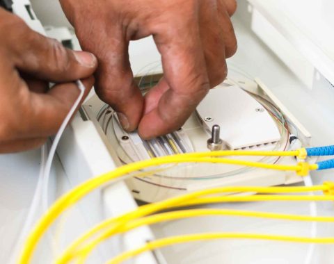 A pair of hands installing fiber optic cables